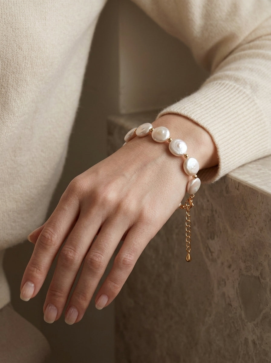 Lifestyle shot of the Selene coin pearl bracelet on a woman's wrist, showcasing its sleek, low-profile elegance and natural glow.