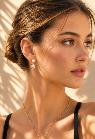 A lifestyle shot of the Eirene fissured texture earrings styled with a minimalist outfit. The image demonstrates the artistic drop length and how the vintage gold finish complements a warm, sophisticated skin tone.