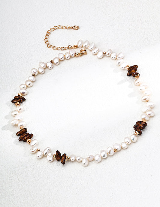 A crisp studio shot of the Cyra necklace on a neutral background. This main image clearly displays the high-luster 5mm pearls and the 1.2x0.6cm Tiger's Eye accents, emphasizing the artisanal quality of the 18K gold-plated S925 silver chain.
