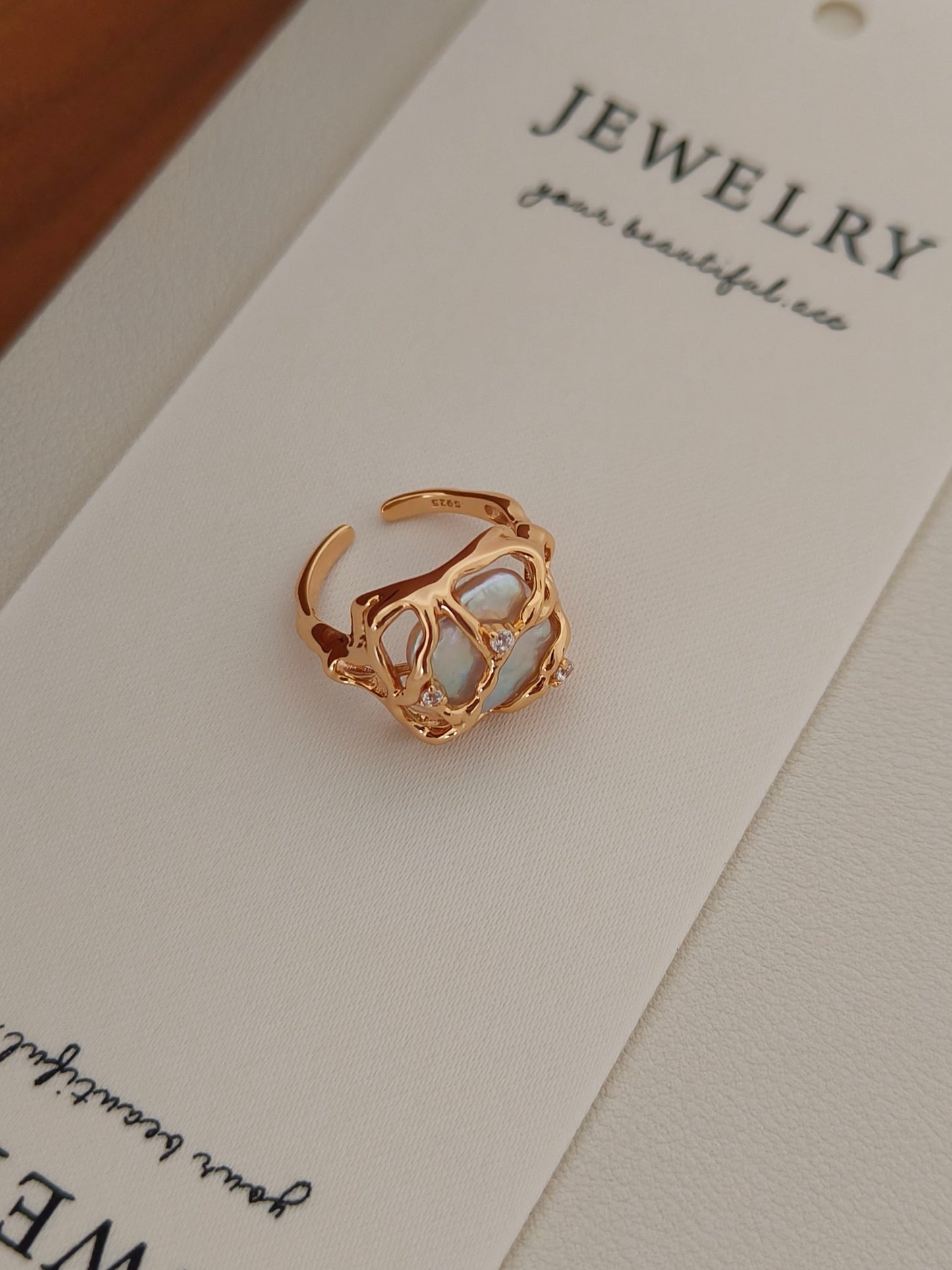 Detailed view of the Terra woven ring on a Vera Lustre jewelry card, showcasing the organic texture of the gold cage and the unique pearl shape.