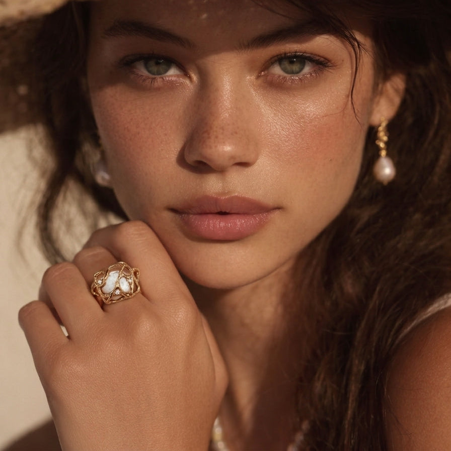 A lifestyle shot of a woman wearing the Terra woven pearl ring and Gaia earrings, embodying a sun-drenched, sophisticated summer aesthetic.