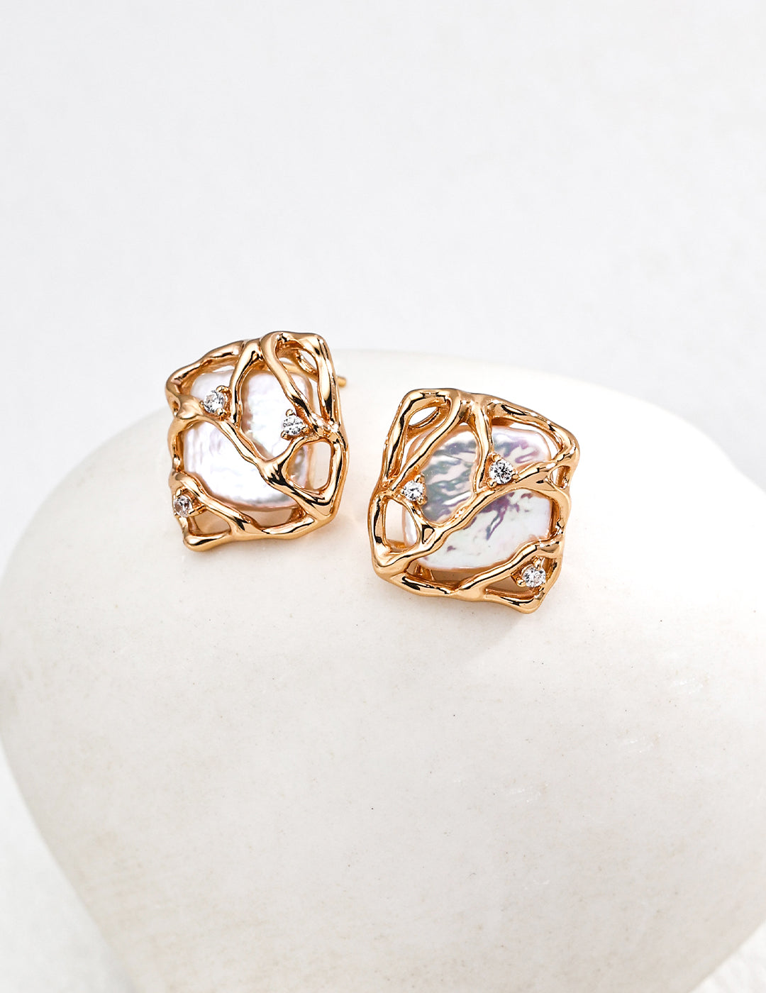 Vera Lustre "Gaia" stud earrings featuring unique baroque pearls encased in an intricate 18K gold vermeil woven cage design.