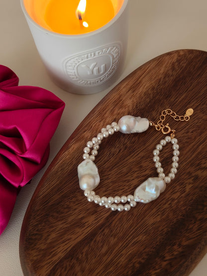 Close-up view of the luminous freshwater pearls and the Vera Lustre quality seal on the 18K gold vermeil extender chain, displayed on a wooden tray with a scented candle.