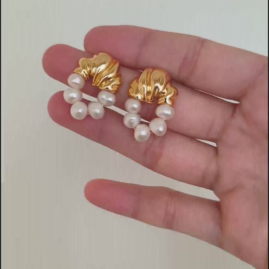 A cinematic video of the Eos earrings in motion. As they sway, the video captures the shifting "orient" of the baroque pearls and the brilliant reflection of the golden hardware, demonstrating their dynamic elegance.