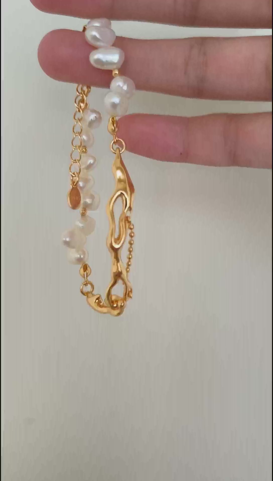 A cinematic video of the Astraea bracelet shimmering under natural light, capturing the iridescent depth of the pearls and the liquid-like movement of the gold links.