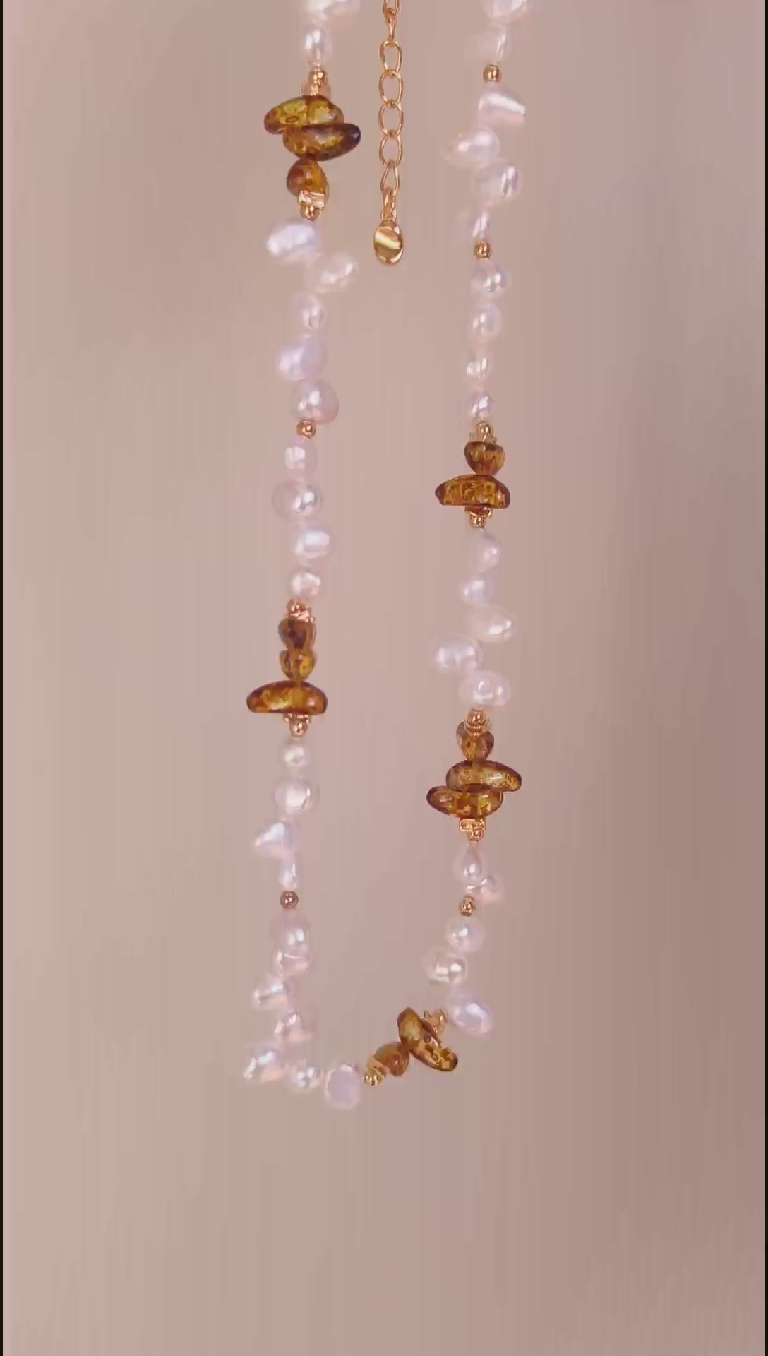 A cinematic video of the Cyra necklace in motion. As the piece moves, the light dances across the chatoyant Tiger's Eye and the iridescent baroque pearl, illustrating the dynamic, "living" energy of the natural materials.