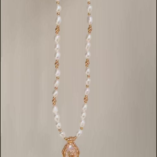 This cinematic video pans across the Elara necklace, capturing the shifting iridescence of the Mother-of-Pearl and the radiant glow of the pearl strand. The movement highlights the elegant drape of the 38cm chain and the shimmering details of the vintage medallion as it catches the light.