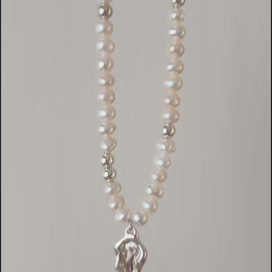 This cinematic close-up video captures the Serene necklace in motion, showing light dancing across the fluid lake medallion. The movement emphasizes the iridescent luster of the 5-5.5mm pearls and the high-shine polish of the silver hardware, illustrating the piece's vivid quality.