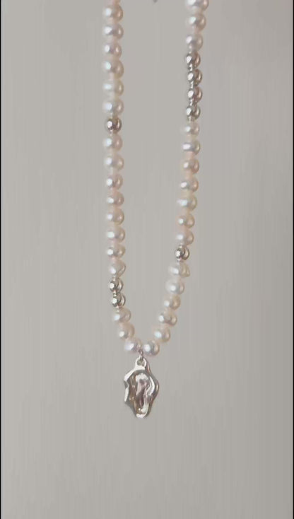 This cinematic close-up video captures the Serene necklace in motion, showing light dancing across the fluid lake medallion. The movement emphasizes the iridescent luster of the 5-5.5mm pearls and the high-shine polish of the silver hardware, illustrating the piece's vivid quality.