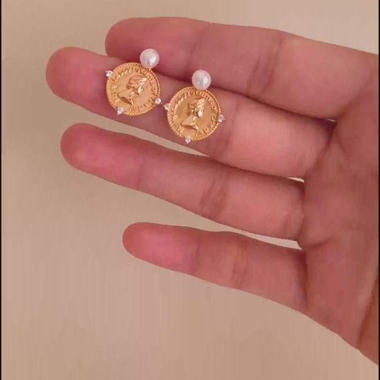 A cinematic video showing the Aurelia earrings in motion. The footage captures the high-polish reflection of the 18K gold plating and the fluid swing of the pearls, demonstrating their dynamic, eye-catching elegance.