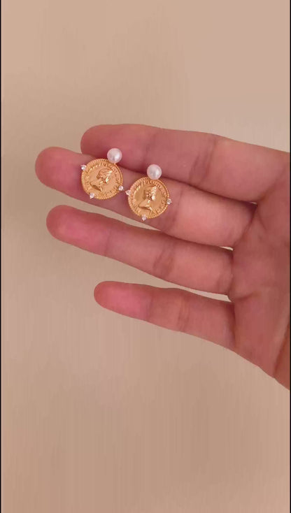 A cinematic video showing the Aurelia earrings in motion. The footage captures the high-polish reflection of the 18K gold plating and the fluid swing of the pearls, demonstrating their dynamic, eye-catching elegance.