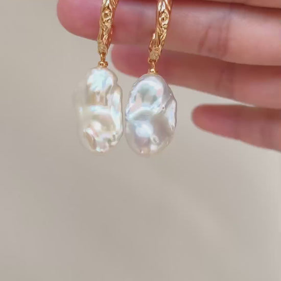 A cinematic video showing the Calliope earrings in motion. The footage captures the way the light dances across the uneven surfaces of the pearls, highlighting their natural iridescence and fluid movement.