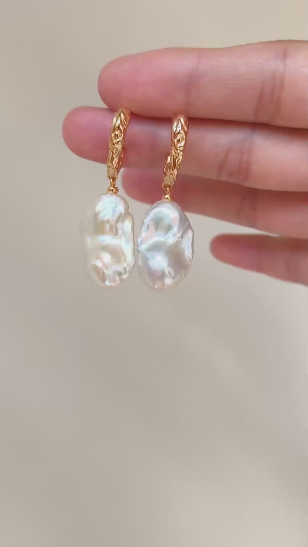 A cinematic video showing the Calliope earrings in motion. The footage captures the way the light dances across the uneven surfaces of the pearls, highlighting their natural iridescence and fluid movement.