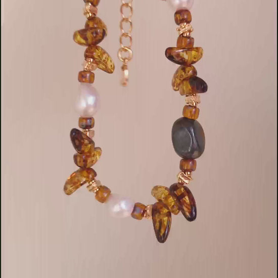 A cinematic video of the Cybele bracelet in movement. The footage captures the "cat-eye" effect of the Tiger's Eye and the shimmering light reflecting off the Czech glass and pearls.