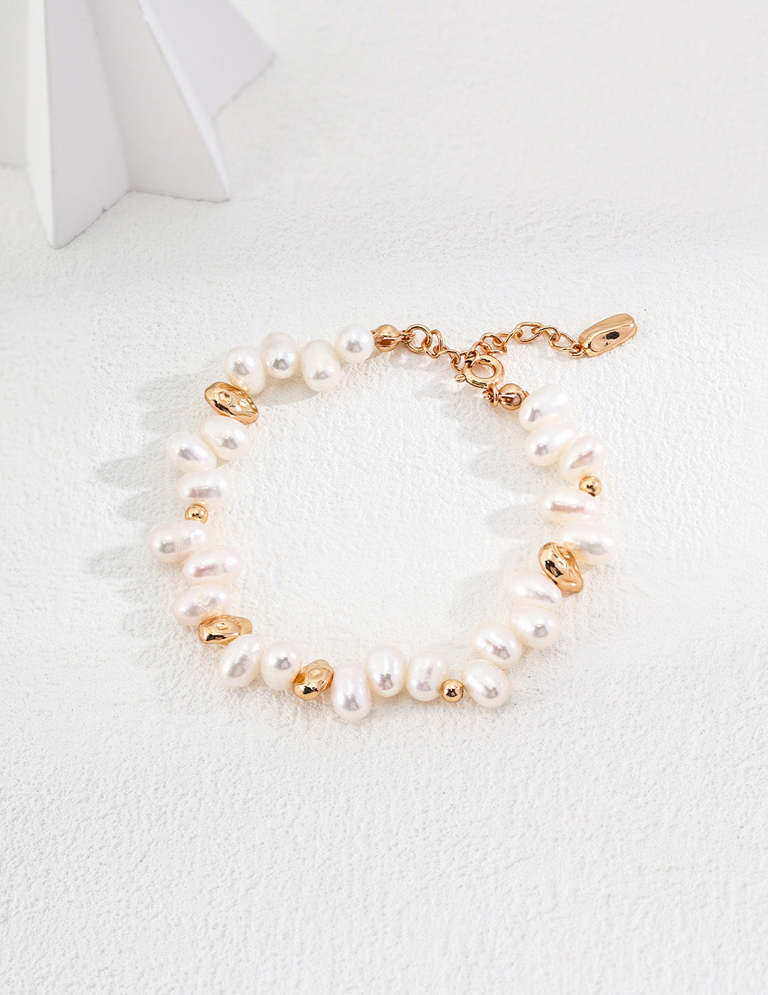 A professional studio shot of the Clémentine bracelet, highlighting the raw, non-uniform shapes of the natural pearls and the matching gold nugget accents.