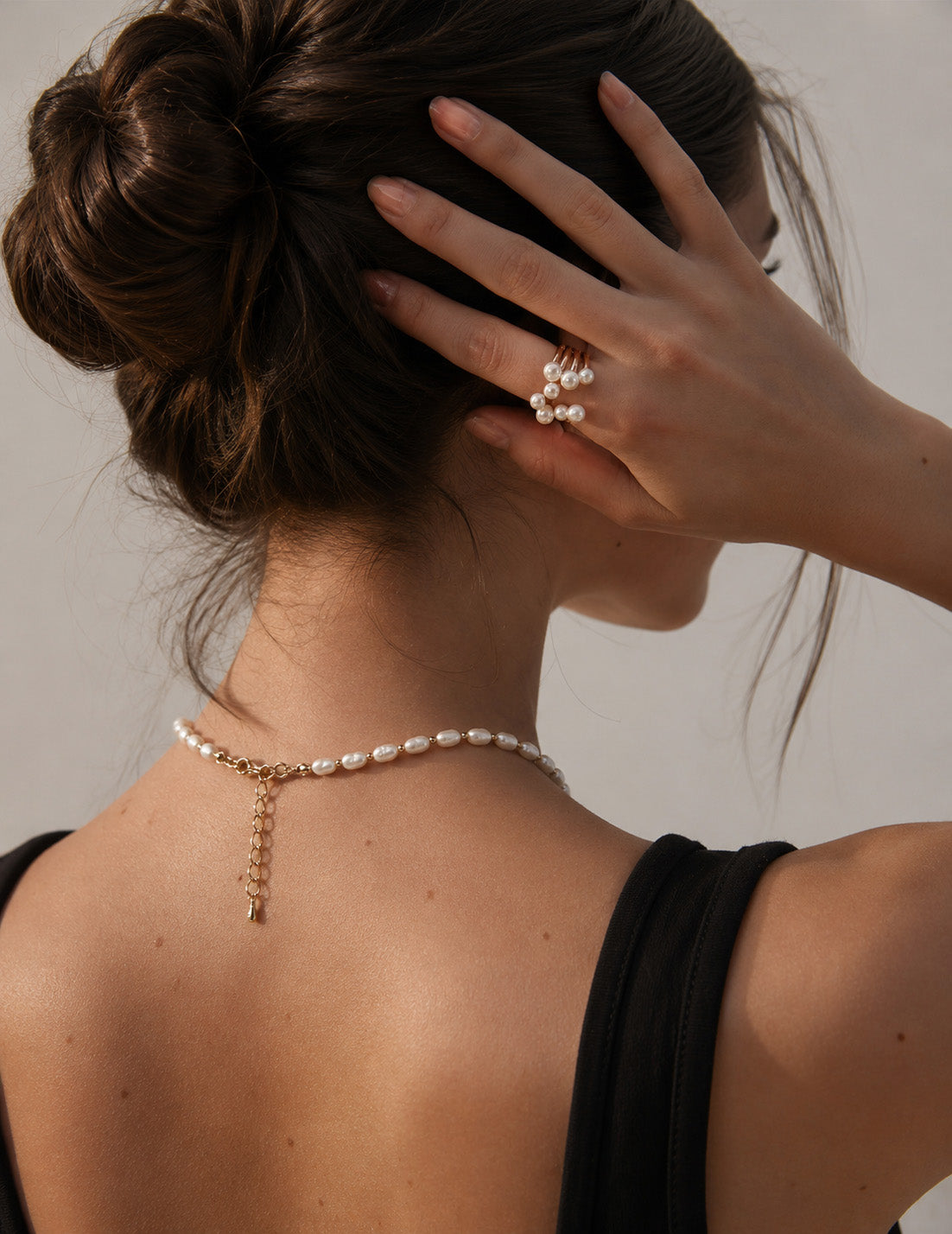 A close-up of a model's hand styled with the Sia ring, showcasing how the organic pearl focal point adds a touch of French-chic sophistication to a minimal look.
