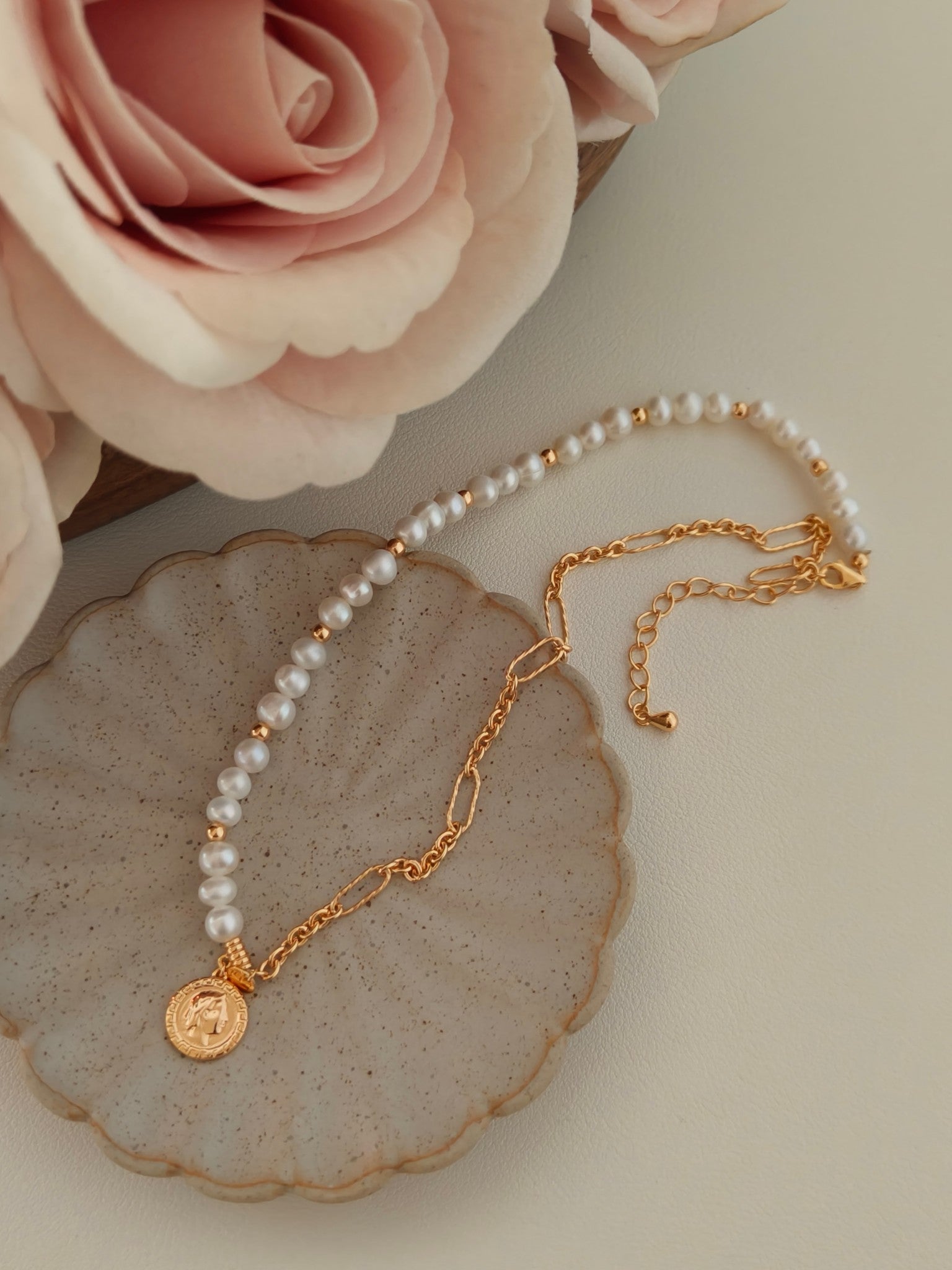 A macro close-up focusing on the hand-selected baroque pearls and the intricate relief of the gold Queen coin charm. The image displays the authentic textures and "natural imperfections" that make each necklace unique. This detailed view reinforces the product's luxury value, highlighting the thick 18K gold over 925 sterling silver (gold vermeil) and the secure, hypoallergenic hardware designed for long-lasting, comfortable daily wear.