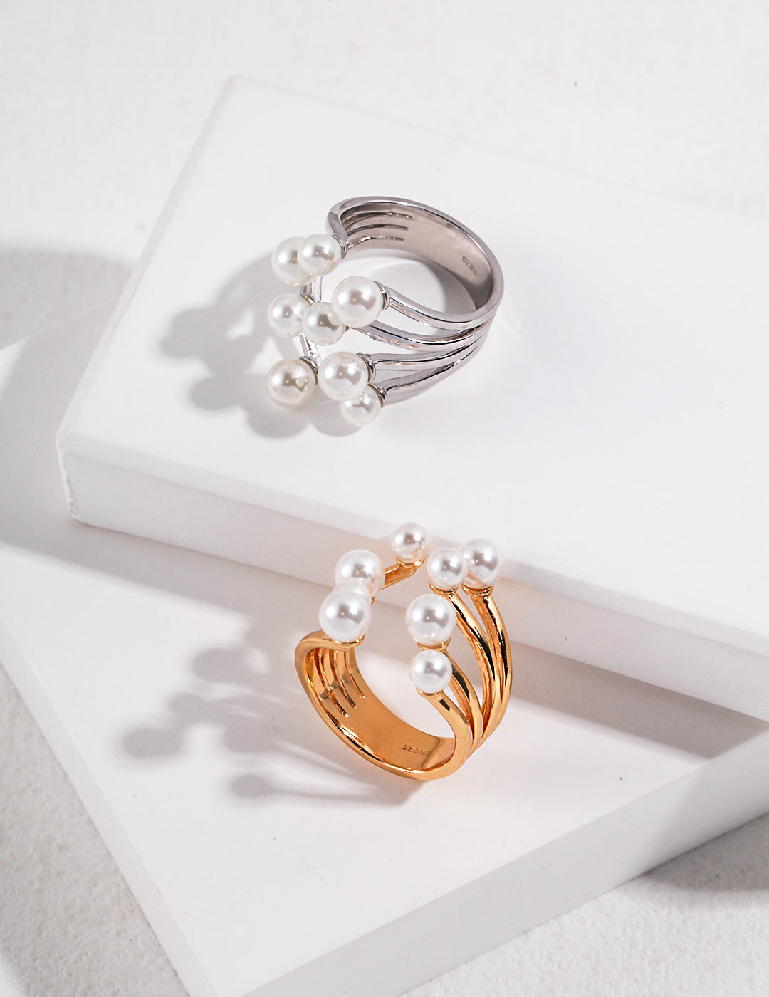 A lifestyle shot of the Sia pearl ring worn on the index finger, demonstrating its adjustable open-band fit and elegant, bypass sculptural silhouette.