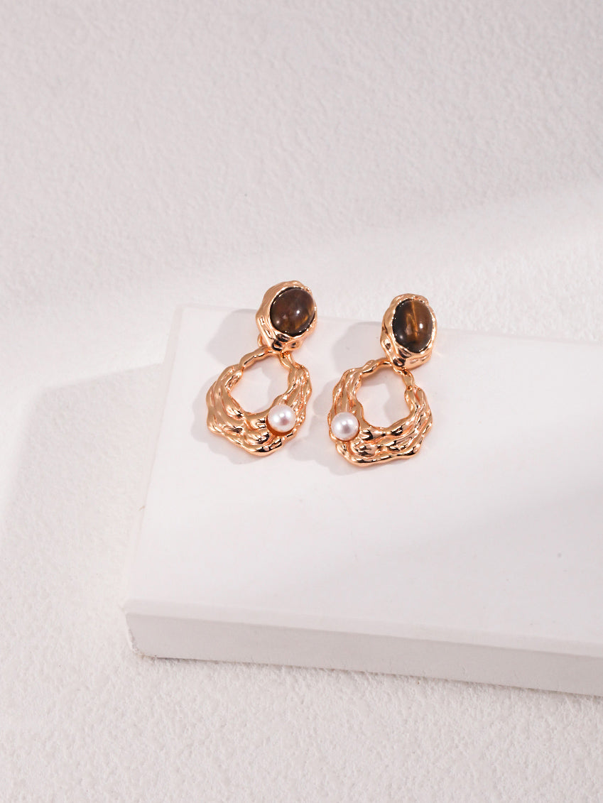 A professional studio shot of the Gaia earrings, showcasing the high-contrast beauty of the 6mm Tiger's Eye and the 4mm freshwater pearl. This image highlights the S925 silver vintage gold craftsmanship.