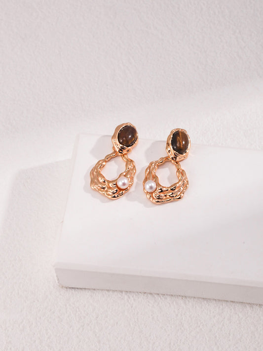 A professional studio shot of the Gaia earrings, showcasing the high-contrast beauty of the 6mm Tiger's Eye and the 4mm freshwater pearl. This image highlights the S925 silver vintage gold craftsmanship.