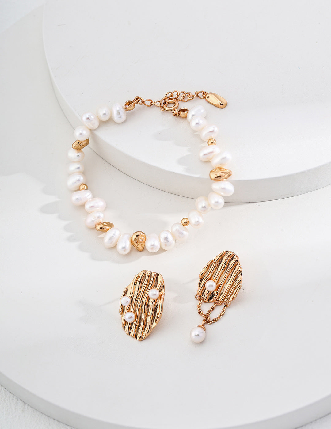 An overhead view of the bracelet and earrings laid flat, showing the rhythmic alternation between the lustrous pearls and the vintage gold hardware.
