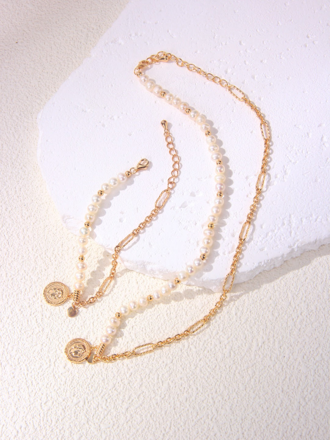 A curated flat lay of the Calyx collection, featuring the asymmetric necklace paired with the matching pearl nugget bracelet. This visual highlights the cohesive design language of Vera Lustre, emphasizing the value of purchasing a coordinated set. It targets searchers interested in luxury jewelry sets and handcrafted gold vermeil accessories, illustrating the premium craftsmanship and consistent quality across the brand’s signature baroque series.