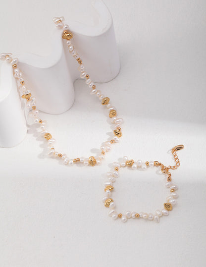 An overhead view of the bracelet and necklace laid flat, showing the rhythmic alternation between the lustrous pearls and the vintage gold hardware.