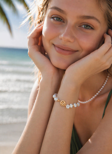 A lifestyle shot showing the Elowen baroque pearl bracelet gracefully layered on a model's wrist, highlighting its delicate scale and the radiant 18K gold finish.