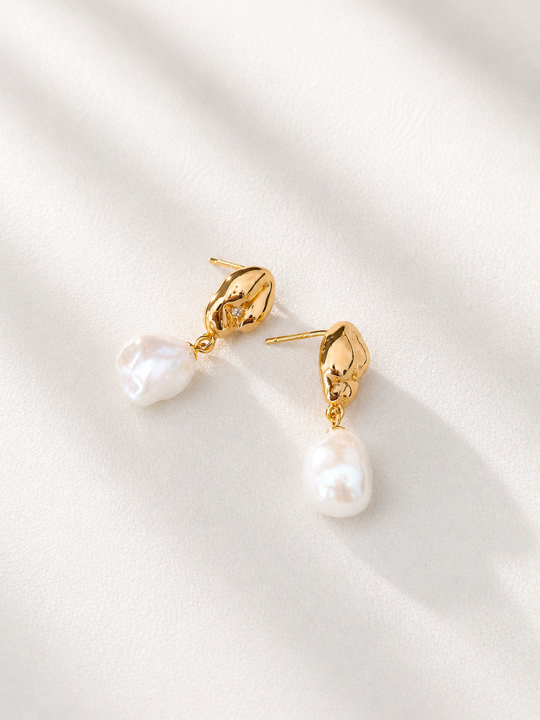 A side view of the pearl drops, focusing on the fine S925 sterling silver craftsmanship and the minimalist aesthetic of the gold setting.