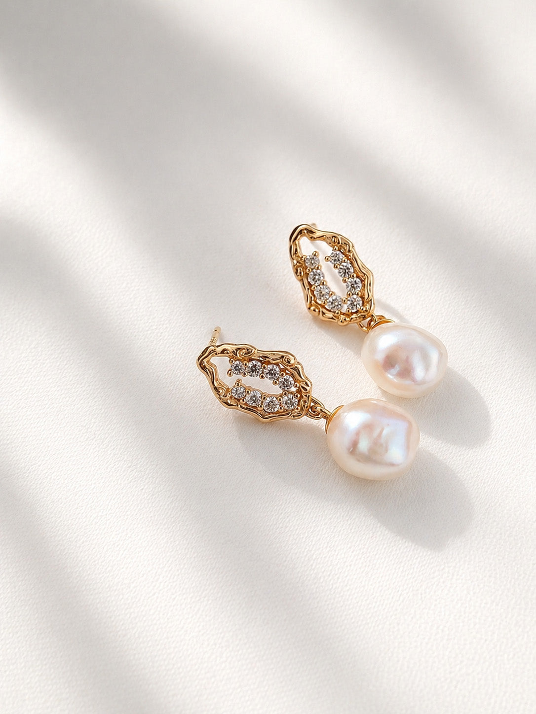A clean studio shot of the Selene pearl drops, highlighting the distinct, organic shapes of the freshwater baroque pearls. This primary image emphasizes the S925 sterling silver craftsmanship and the rich golden tone.