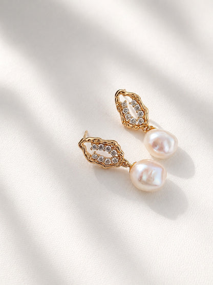 A clean studio shot of the Selene pearl drops, highlighting the distinct, organic shapes of the freshwater baroque pearls. This primary image emphasizes the S925 sterling silver craftsmanship and the rich golden tone.