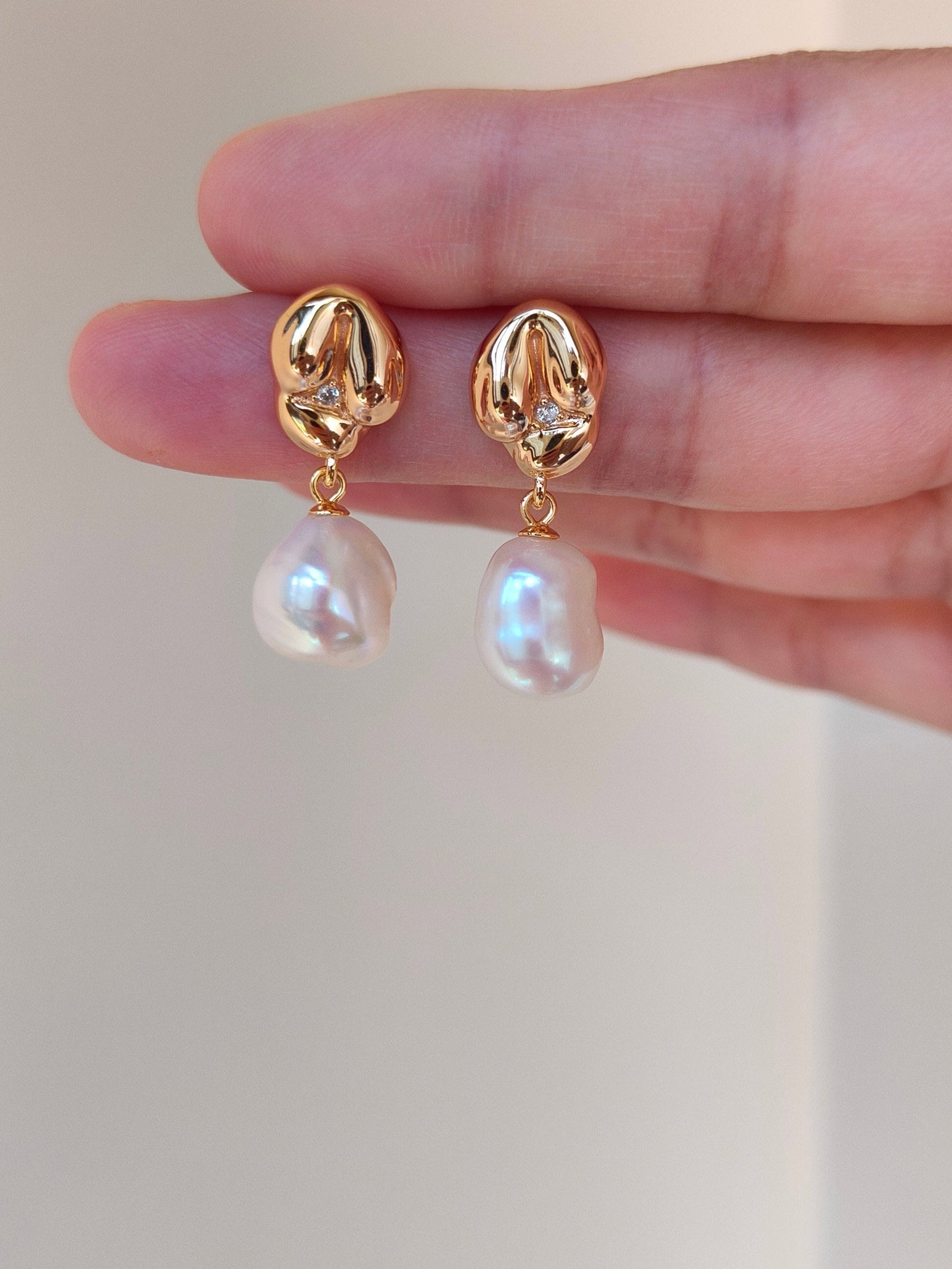 A close-up of the earring pair, showcasing the quality of the 18K gold finish and the authentic, creamy white tones of the pearls.