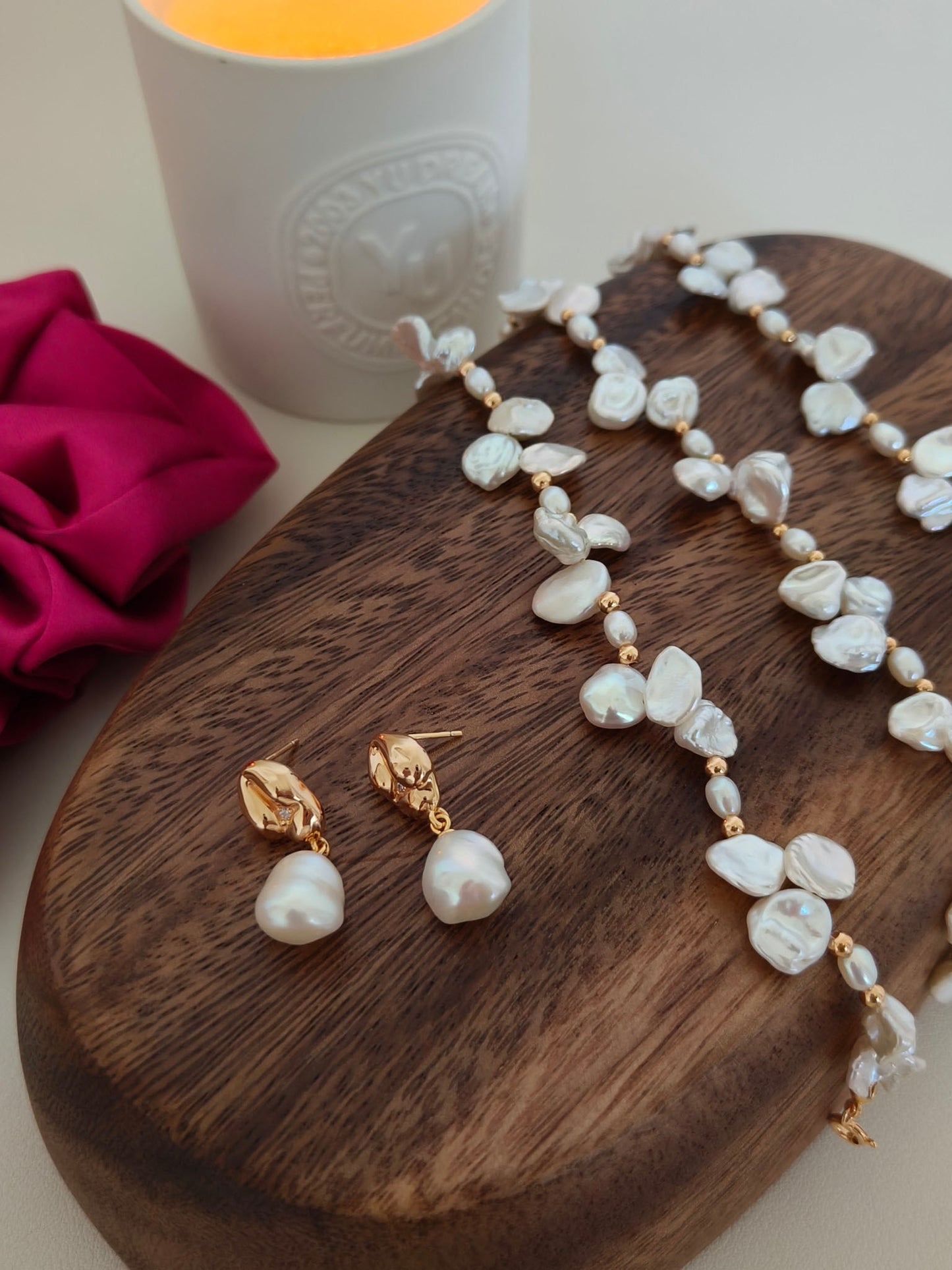 A lifestyle arrangement of the pearl earrings alongside other gold accessories, showcasing their perfect suitability for stacking and layering styles.