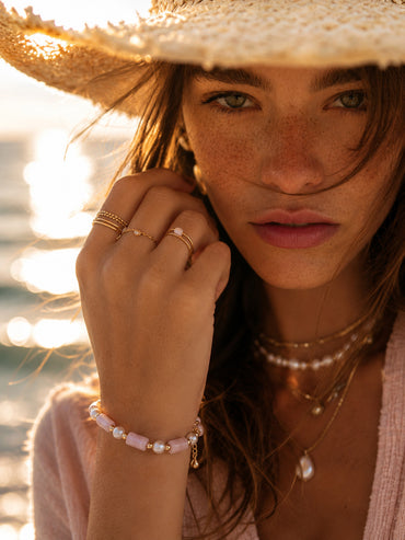 A lifestyle shot of the Liora Kunzite bracelet on a wrist, capturing the soft lavender gemstones and baroque pearls glowing under natural sunlight.