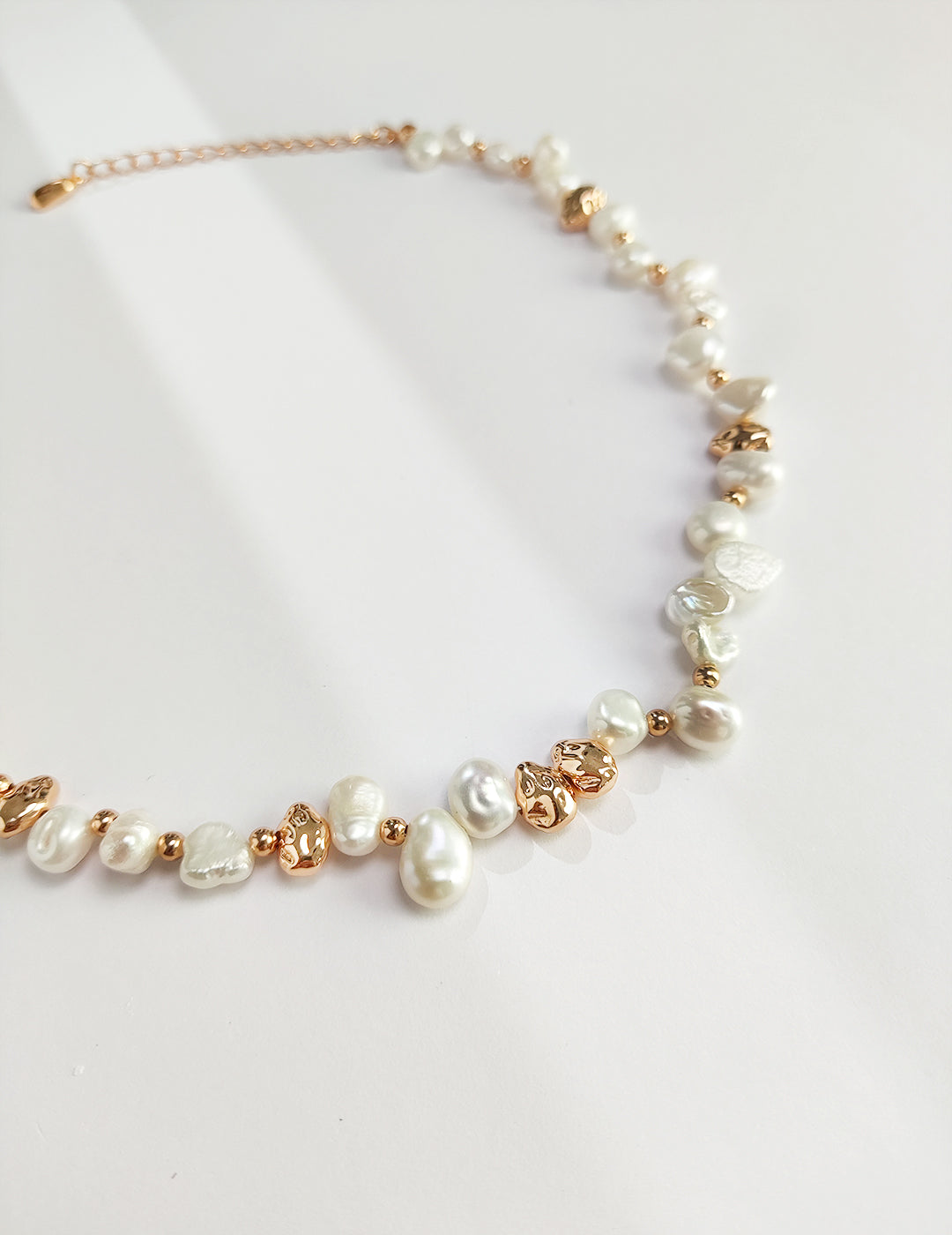 A macro close-up focusing on the unique, organic silhouettes of the natural freshwater pearls. The detail captures the mirror-like luster and the intricate, weathered textures of the vintage gold silver hardware, targeting customers who appreciate authentic, high-quality materials.