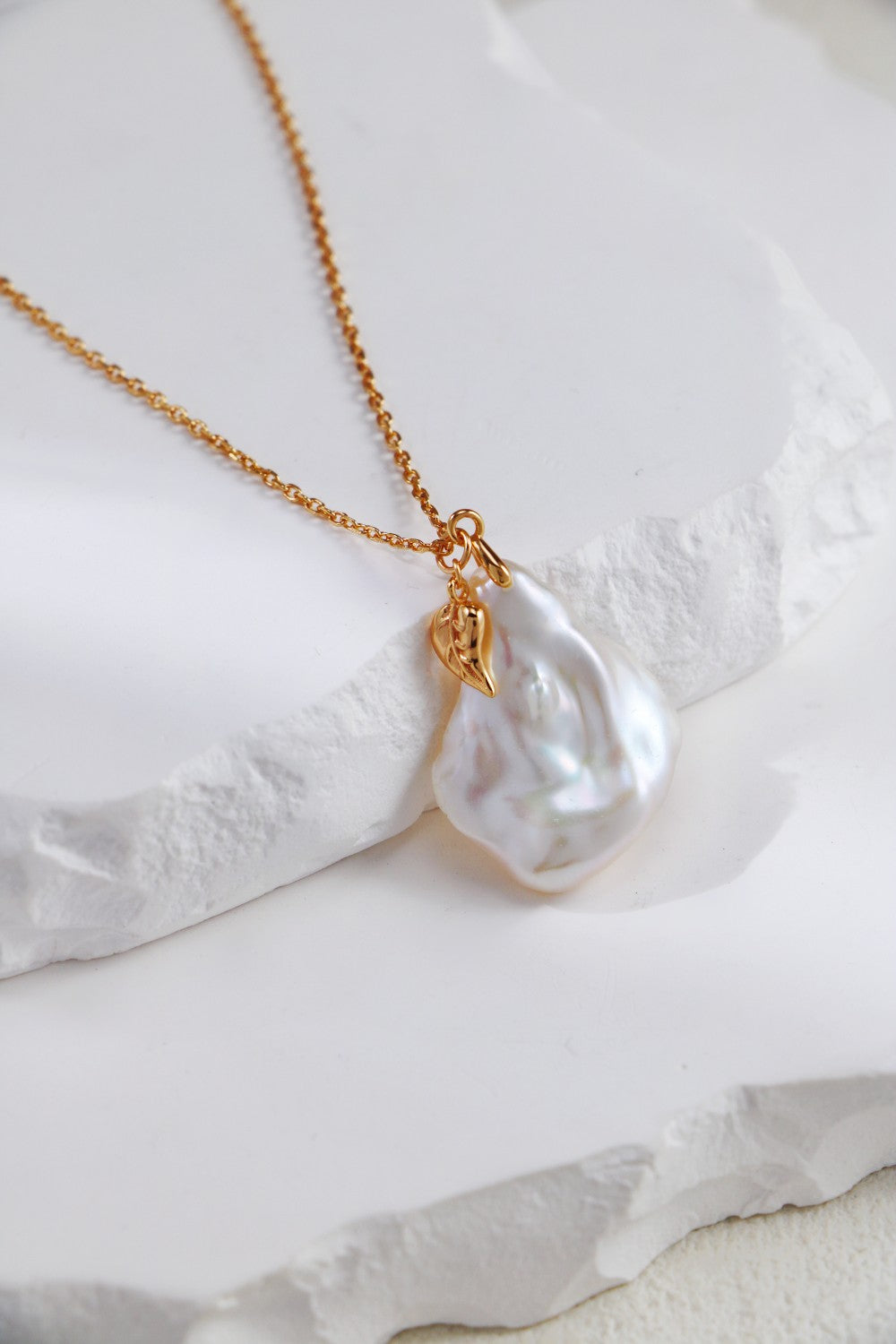 A professional studio shot of the Flora necklace in vintage gold. This image showcases the "petal" geometry of the central pearl and the lustrous 4-5mm pearl chain, emphasizing the brand's focus on one-of-a-kind artisan jewelry.