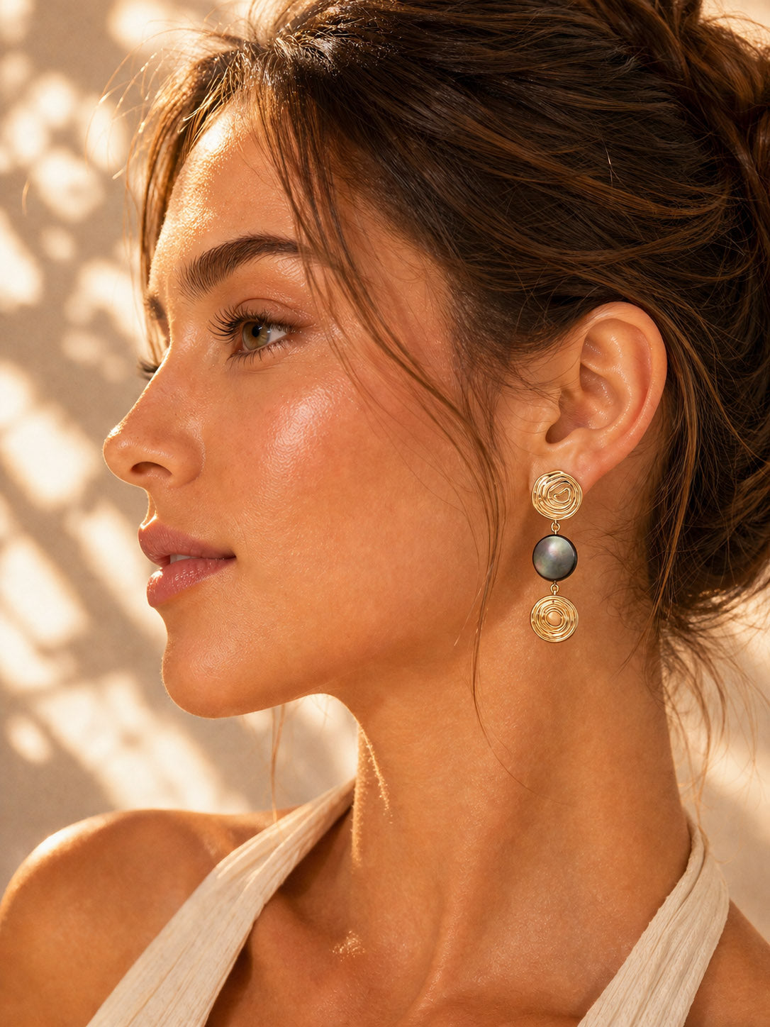 A lifestyle shot of the Nyx black shell drops worn by a model. The visual highlights the sleek 4cm elongation and how the dark iridescence adds a mysterious, high-fashion edge to the profile.