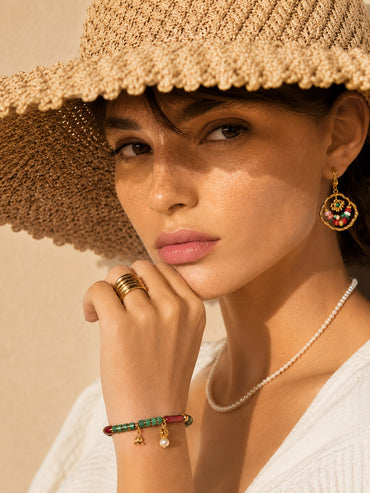 A lifestyle shot of the Iris colorful gemstone bracelet on a wrist, showcasing the vibrant red agate and green shell beads catching the sunlight for a bohemian look.