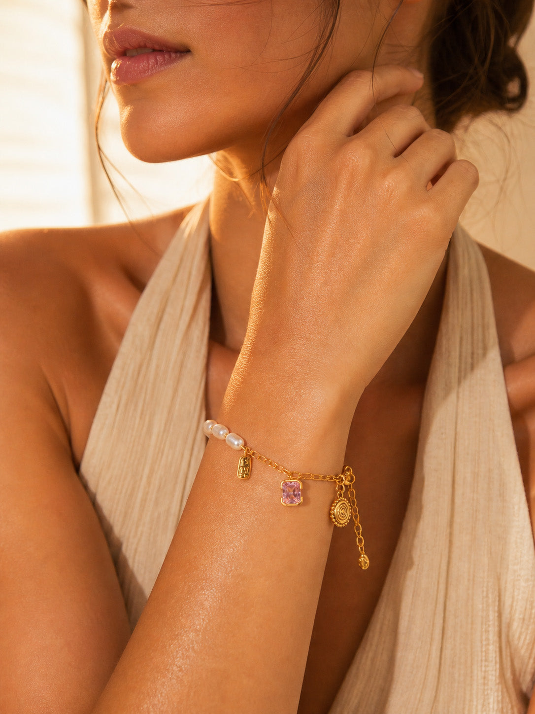A lifestyle shot of the Seraphina pearl and zircon bracelet styled on a wrist. The visual highlights the delicate drape of the chain and how the 18K gold finish glows against the skin.