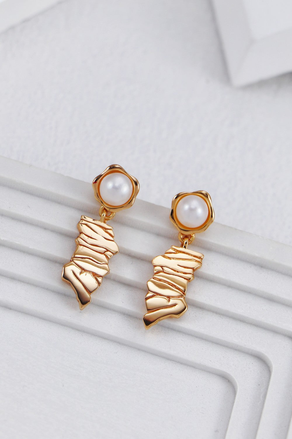 A clean studio shot of the Eirene earrings, highlighting the intricate irregular line design and the creamy, iridescent luster of the natural pearl drops.