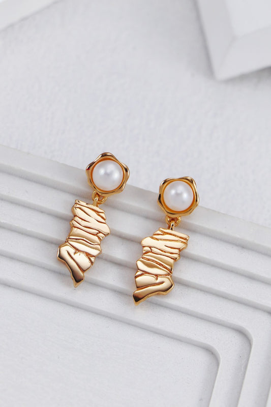 A clean studio shot of the Eirene earrings, highlighting the intricate irregular line design and the creamy, iridescent luster of the natural pearl drops.