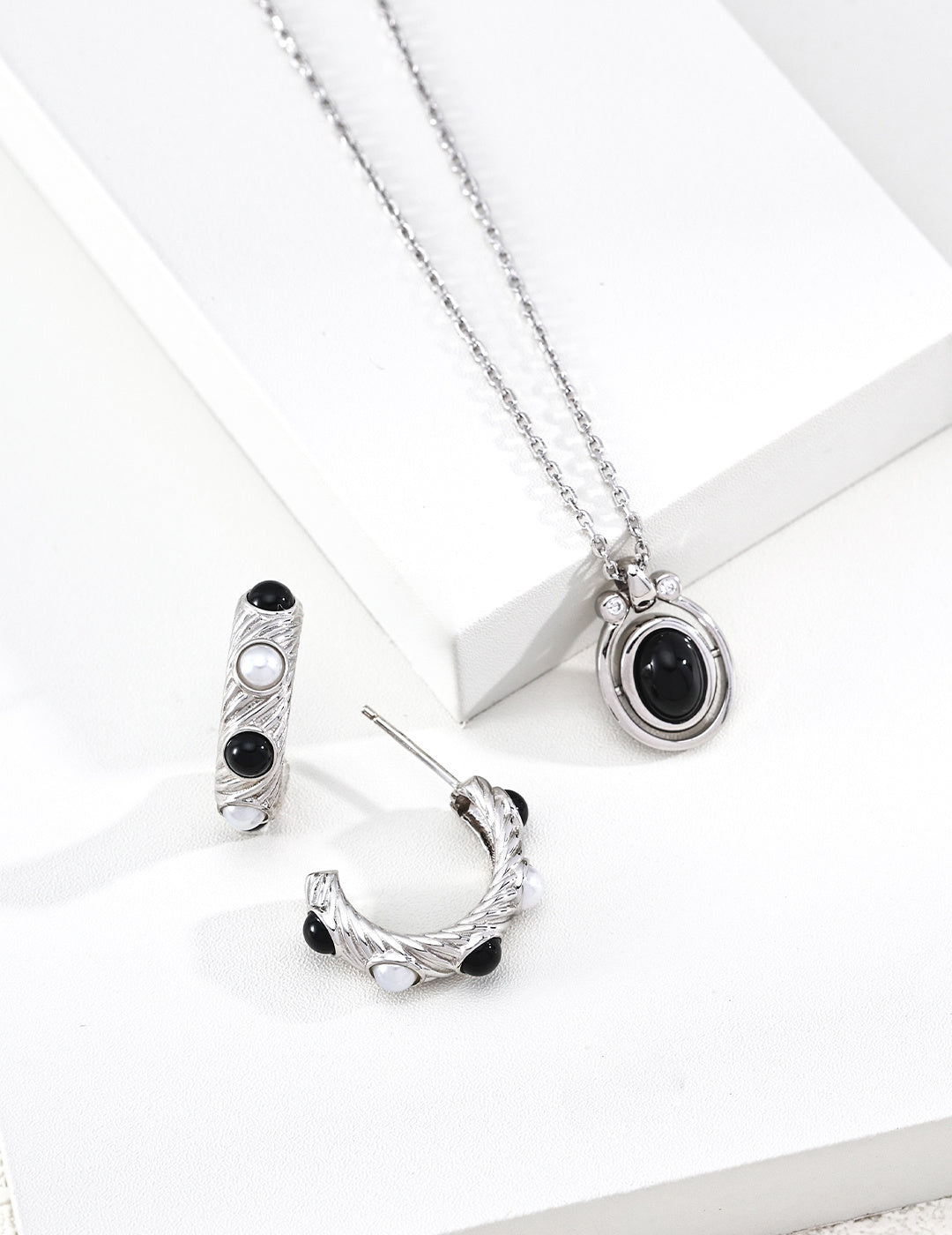 A crisp close-up focusing on the Black Agate variant of the Astra necklace. The deep, obsidian hue of the stone is contrasted by a halo of sparkling cubic zirconia, emphasizing the handcrafted S925 sterling silver base and the premium artisanal finish of the rotating mechanism