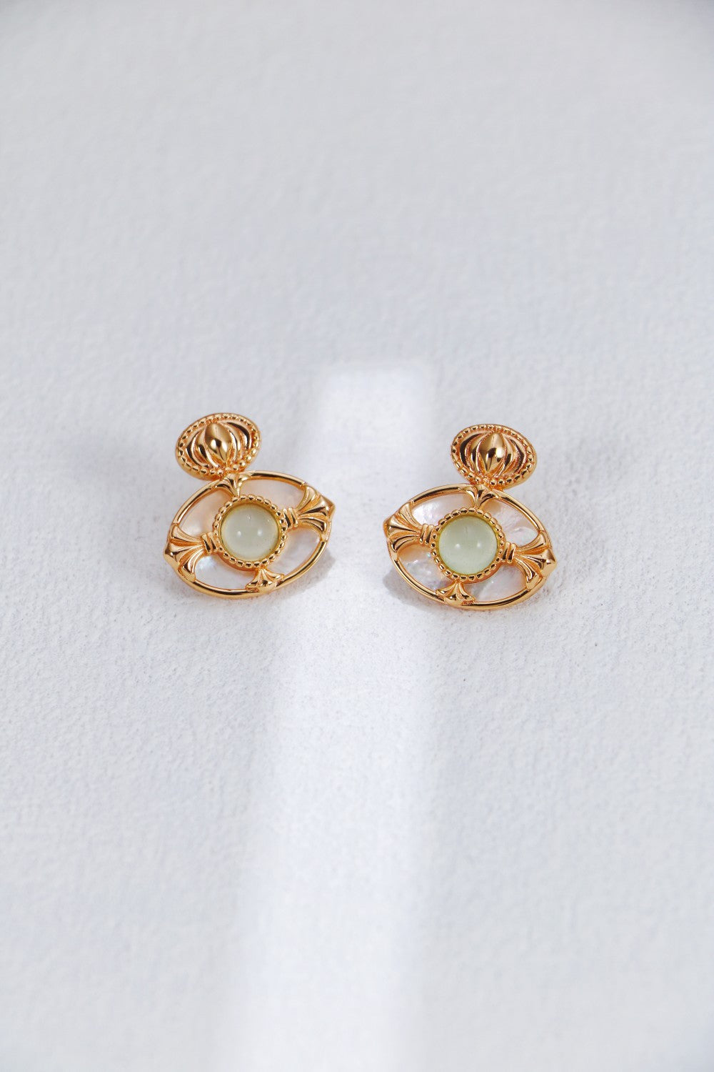 A professional studio shot of the Artemis earrings, showcasing the high-polish finish of the Green Chalcedony and the creamy, shifting luster of the Mother-of-Pearl border.