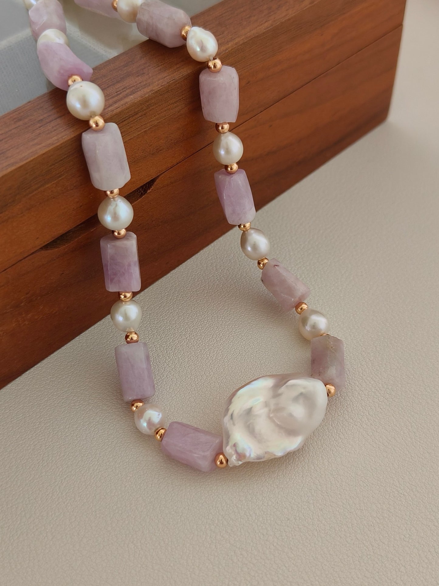 A macro close-up of the natural lepidolite and baroque pearl connection. The detail reveals the authentic textures and rich lilac hues of the healing gemstones, targeting customers looking for metaphysical jewelry with premium artisanal finishing.