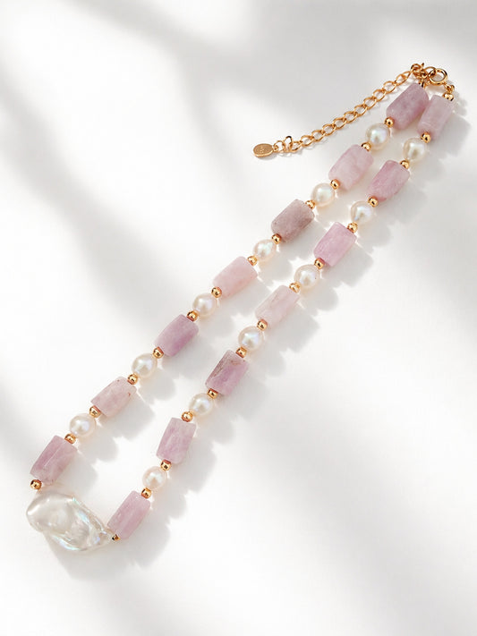 A high-resolution studio shot of the Amoris necklace on a clean surface. This main image clearly displays the unique cylindrical lepidolite and the oval baroque pearl centerpiece, emphasizing the handcrafted 18K gold vermeil quality and organic silhouette.