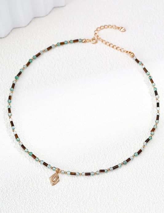 A high-resolution studio shot of the Gaia necklace on a clean surface. This main image clearly displays the rhythmic pattern of 3mm green quartz and sculptural Tiger's Eye stones, emphasizing the handcrafted S925 silver quality and vintage gold finish.