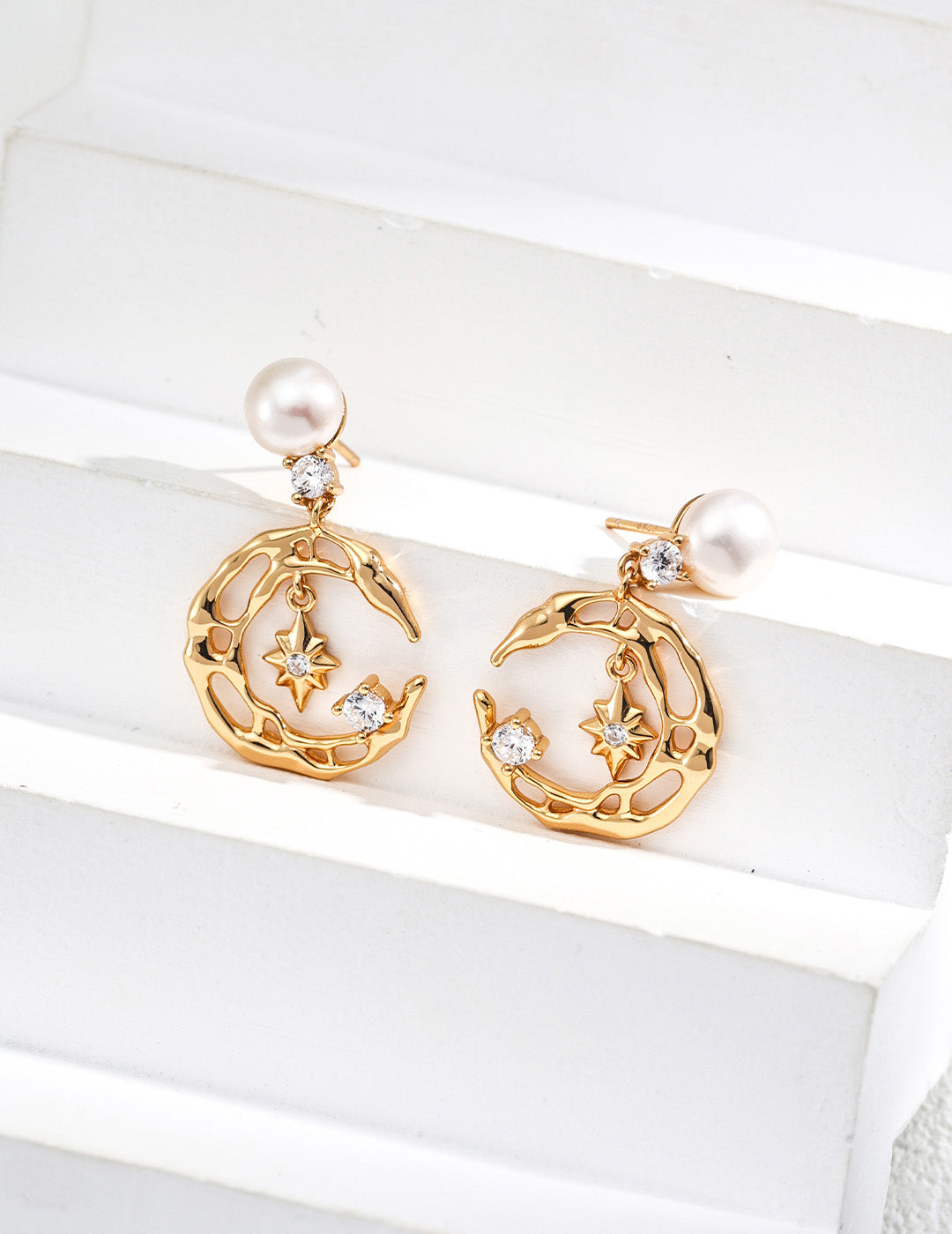 A professional studio shot of the Astra earrings, highlighting the intricate CZ pavé-set star and the high-orient luster of the 7mm natural freshwater pearl drops.