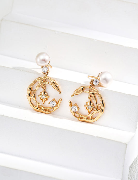 A professional studio shot of the Astra earrings, highlighting the intricate CZ pavé-set star and the high-orient luster of the 7mm natural freshwater pearl drops.