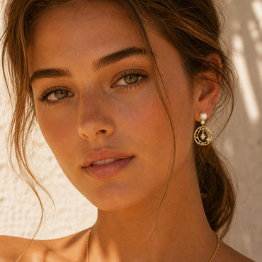 A lifestyle shot of the Astra celestial earrings worn by a model. The visual demonstrates the 3cm drop and how the sparkling star and moon motifs capture the light to illuminate the face with a dreamy, ethereal glow.