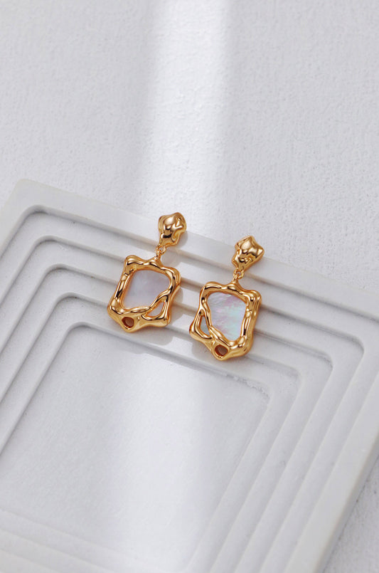 A clean studio shot of the Odyssey earrings, displaying the distorted golden frame and the luminous white shell inlay. This image emphasizes the vintage gold S925 silver quality.